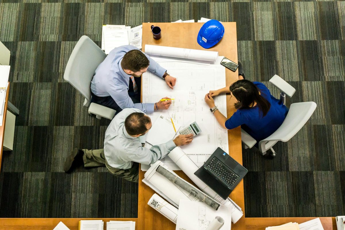 pexels-photo-416405-416405 Top view of a team working on construction plans in an office setting.