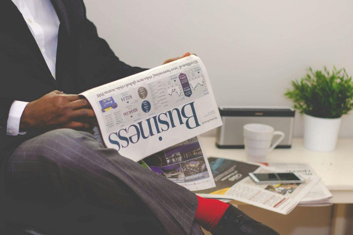 pexels-photo-935979-935979 Businessman reading a financial newspaper at a desk, highlighting finance and commerce theme.